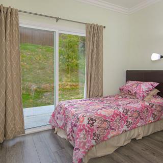 A minimalist bedroom with a single bed featuring floral bedding and large sliding glass doors.