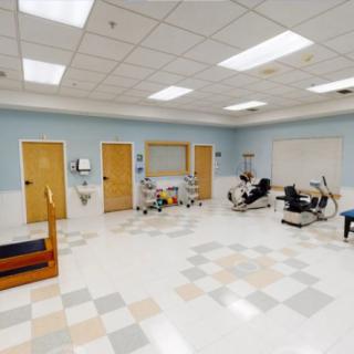 A spacious rehabilitation room equipped with various exercise machines and equipment for physical therapy.
