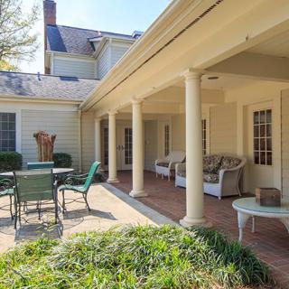 A cozy patio area with outdoor seating and a table, featuring classic columns.