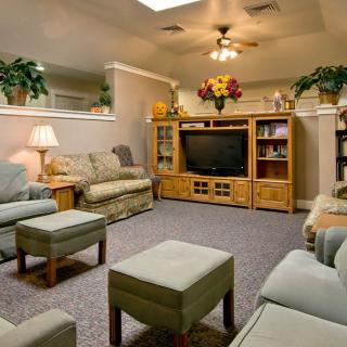 A cozy living room with comfortable seating, a television, and decorative plants.