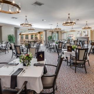 An elegant restaurant dining area with neatly arranged tables and chairs, decorated with chandeliers.