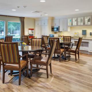 A spacious dining area with modern furniture and a small kitchen setup.