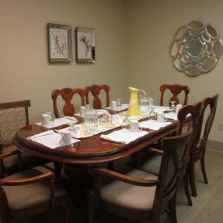 A dining room with a wooden table set for a meal, surrounded by chairs and adorned with wall art.