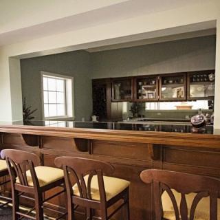 A cozy home kitchen with a wooden bar counter and chairs.