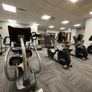 A modern gym with various exercise machines, including stationary bikes and ellipticals.