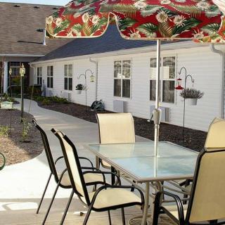 An outdoor patio area with a table, chairs, and an umbrella, adjacent to a residential building.