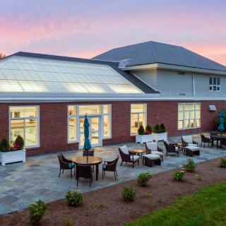 A modern building with outdoor patio seating and landscaped surroundings during sunset.
