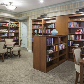 A cozy library with bookshelves and a reading area featuring tables and chairs.
