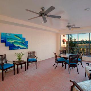 A spacious outdoor patio with seating and dining areas, featuring ceiling fans and vibrant artwork.