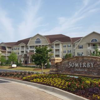 A view of a residential senior living facility with well-maintained gardens and a welcoming entrance.