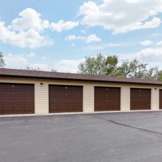 A row of outdoor garage storage units with closed doors.