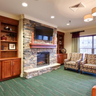 A cozy living room featuring a stone fireplace, comfortable seating, and modern decor.