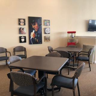 A cozy lounge area featuring tables, chairs, wall decorations, a television, and a popcorn machine.