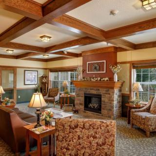 A cozy living room with traditional decor, featuring a fireplace and wood beam ceiling.