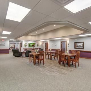 A spacious interior with tables and chairs in a well-lit hallway setting.