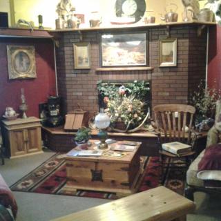A cozy living room with rustic decor, featuring a fireplace surrounded by wooden furniture and various artworks.