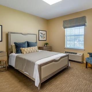 A well-designed bedroom featuring a comfortable bed with decorative pillows, neutral walls, and elegant furnishings.