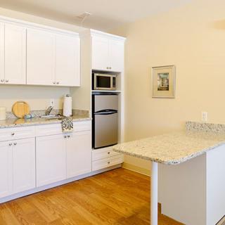 A modern kitchen with white cabinets and built-in appliances.