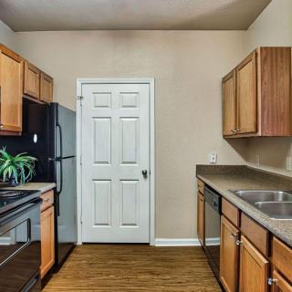 A modern kitchen with wooden cabinets, stainless steel appliances, and a sleek countertop.