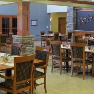An empty restaurant dining area with wooden tables and chairs, ready for service.