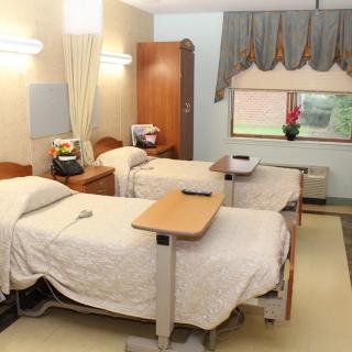 A hospital room featuring twin beds and medical equipment, designed for patient care.
