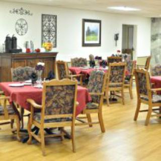 A cozy dining area with wooden tables and chairs, adorned with red tablecloths.