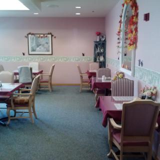 A cozy dining area with pink walls and neatly arranged tables and chairs.