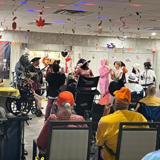 A lively performance entertaining an audience of seniors, decorated for a festive occasion.