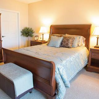 A cozy bedroom with a wooden bed, nightstands, and soft lighting.