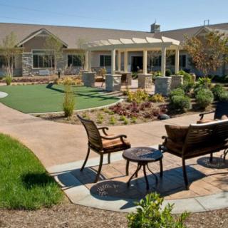 A well-maintained garden with benches and a patio area in front of a building.