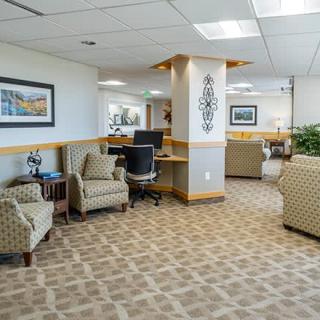 A modern office waiting area with comfortable seating and computer stations.