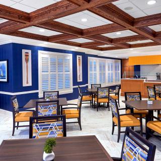 A modern dining area with colorful chairs and a wooden ceiling design.