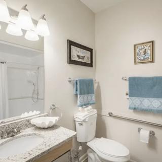 A neatly arranged bathroom with a mirror, sink, toilet, and towels.