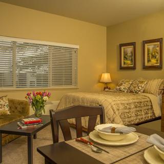 A cozy bedroom with a dining area, featuring warm lighting and elegant decor.