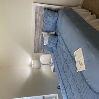 A minimalist bedroom with a blue bedspread and matching pillows, featuring a bedside lamp.