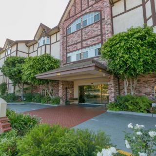 A picturesque entrance to a hotel with a brick facade and lush greenery.