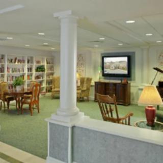 A cozy living room featuring a library area with bookshelves, comfortable seating, and a television.