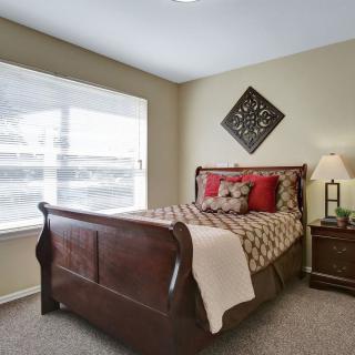 A cozy bedroom with a wooden bedframe, side table, and decorative elements.