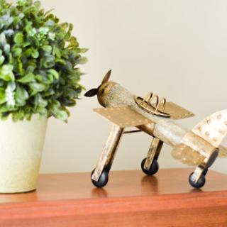 A charming wooden airplane model placed next to a lush green plant, adding a touch of vintage elegance to the interior.
