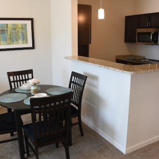 A modern dining area connected to the kitchen, featuring a round table and black chairs.