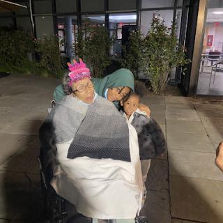A loving moment shared between family members in a wheelchair, providing warmth and comfort on a chilly night.
