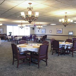 A spacious dining room with multiple round tables and chandeliers.