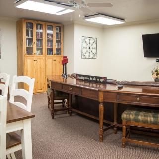 A well-appointed office space featuring a wooden conference table, chairs, a bookshelf, and a TV.
