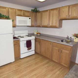 A modern kitchen with wooden cabinets and standard appliances.