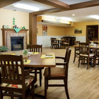 A cozy restaurant dining area featuring wooden tables and chairs, a fireplace, and warm decor.