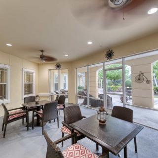 A cozy indoor seating area with tables and chairs arranged near large windows and doors leading to a patio.