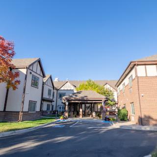 A welcoming entrance to a charming hotel surrounded by greenery and a clear blue sky.