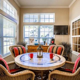 A cozy dining area with a round table and wicker chairs set near large windows, allowing natural light to brighten the space.