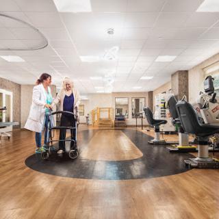 A healthcare professional assists a patient in a rehabilitation facility, showcasing a supportive environment equipped for recovery.