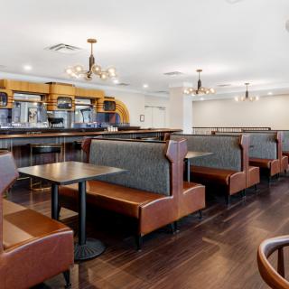 A spacious restaurant interior featuring booths and tables with chandeliers overhead.